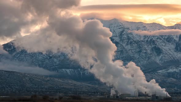 Time lapse of steam from factory rising into the air at sunrise