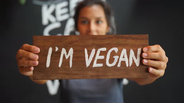 Young Mixed Race Woman Holding Wooden I Am Vegan Sign. Healthy Lifestyle Propaganda Concept