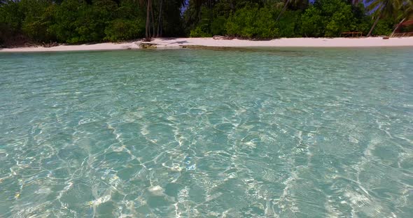 Beautiful flying travel shot of a sunshine white sandy paradise beach and aqua blue water background