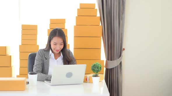 Young Asian entrepreneur girl sitting by the desk with laptop selling online