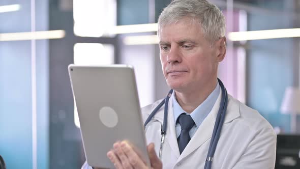 Portrait of Middle Aged Doctor Scrolling on Tablet