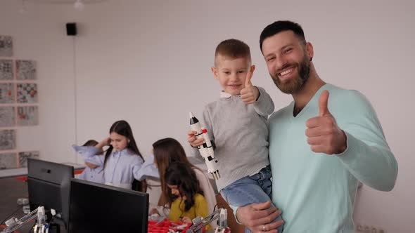 A Portrait of a Smiling Father with a Cute Little Son at a Robotics School