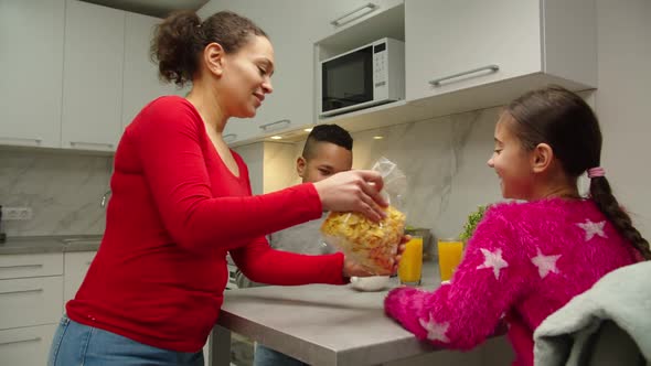 Mother Pouring Cereal to Bowls While Children Sitting at Table Indoors