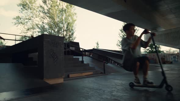 Teenager Riders Practicing Together on Scooter and Skate Board City Skatepark