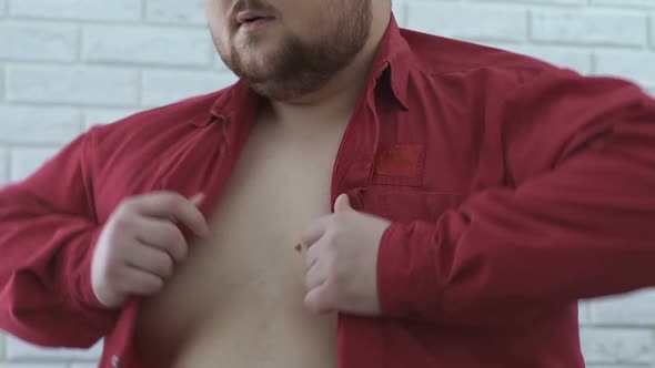 Obese Man Hardly Wearing Shirt on Fat Body, Extra Large Size, Slow-Motion