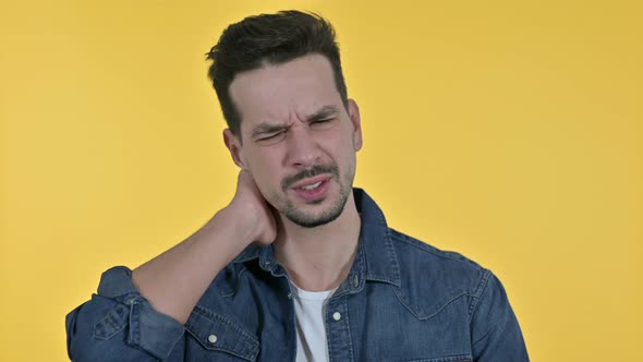 Portrait of Tired Young Man Having Neck Pain, Yellow Background