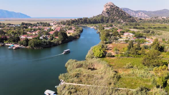 The flight of a drone over a river in a mountainous area along which a boat floats between the banks