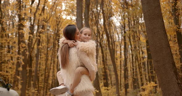 Happy Woman with Little Daughter in Autumn Park