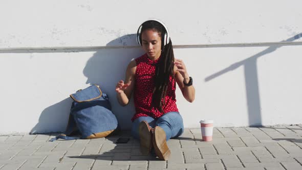 African american woman wearing headphones and listening to music on promenade by the sea