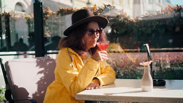 A Mature Adult Woman in a Hat Drinking a Cocktail From the Martini Glass