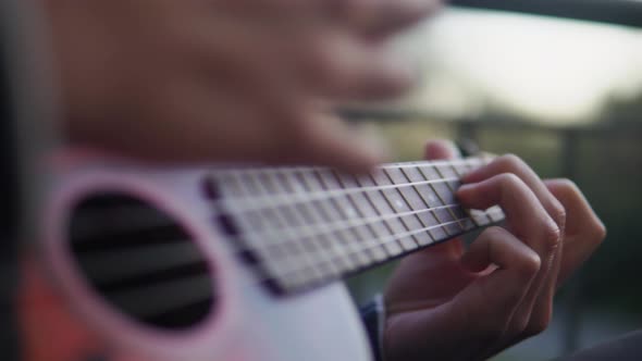 Footage of a women playing the ukulele outside