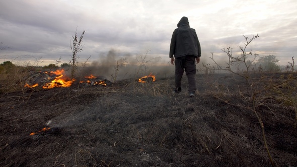 man walks on a burning field in the steppe