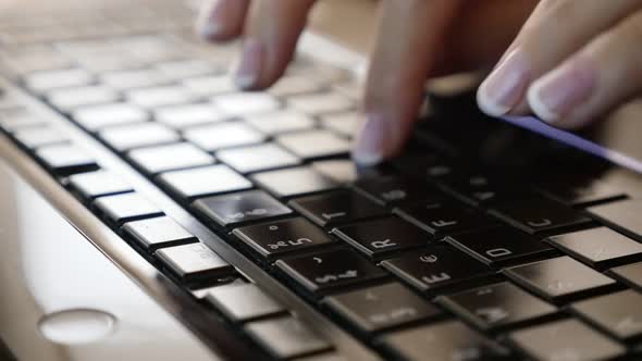 Modern female in office typing on black laptop keyboard close-up slow motion 1080p HD tilting video 