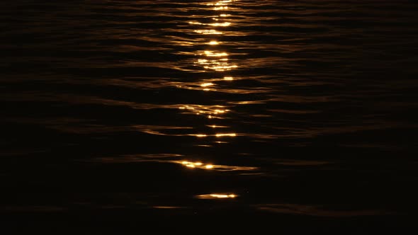 Narrow Beaming Sunlight Path Reflection on Pitch Black Water