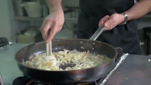 Chef in Restaurant Kitchen at Stove with Pan Doing Flambe on Food