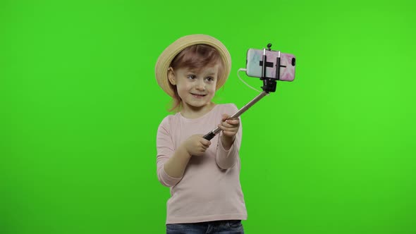 Girl Child Makes Selfie, Blogging on Mobile Phone Using Selfie Stick. Chroma Key