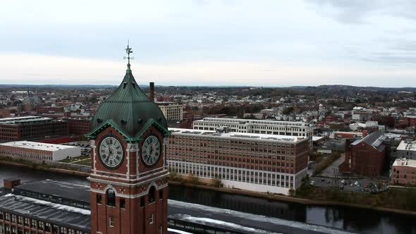 Close Up View Of Ayer Mill Clock Tower With Commercial And Industrial Buildings Along Merrimack Rive