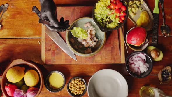 Preparation of ceviche salad - table top down view of a chef scooping brunoise dice green bell peppe