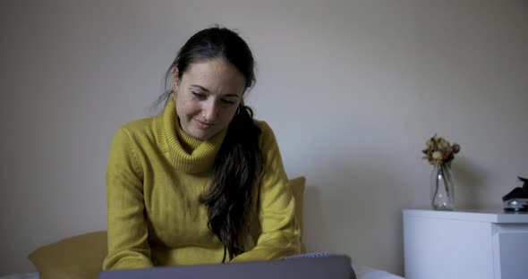 Happy woman with laptop computer on the bed watching movie and navigating onl