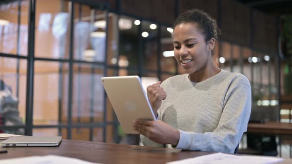 African Woman Celebrating Success on Tablet PC