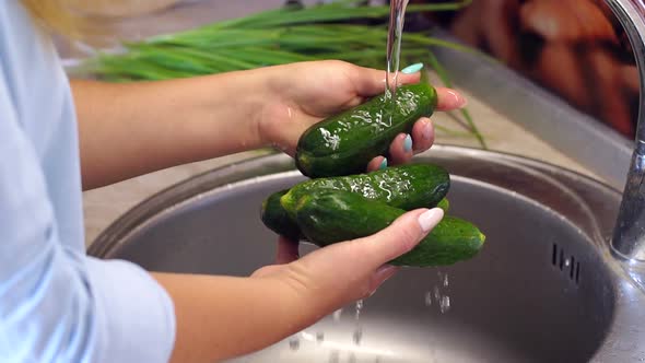 Close-up of a Woman Washing Fresh Cucumbers in the Kitchen Sink.