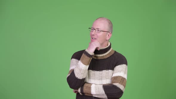 Happy Mature Bald Man with Turtleneck Sweater Thinking While Looking Up