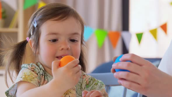 Baby Girl and Mother Beating Easter Eggs at Home