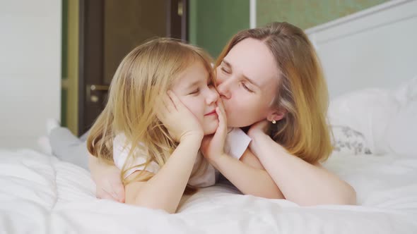 Mom and Daughter in Bed Having Fun Kissing and Hugging