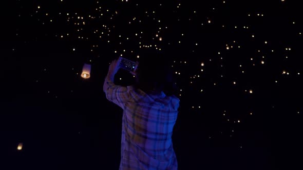 Asian woman watches as sky lanterns fly Into the night sky