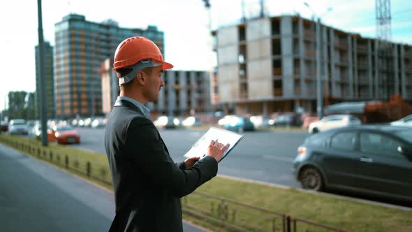 Construction Worker. Architect Look at Paper Plan of Building alt