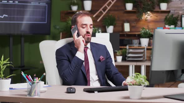 In Modern Office, After Work Hours, a Businessman Is Talking on the Phone