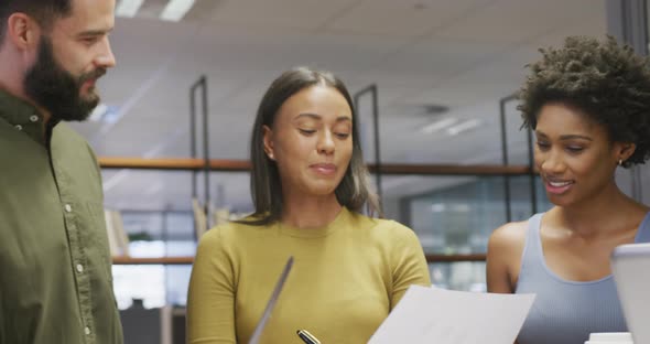 Diverse male and female business colleagues talking and holding documents