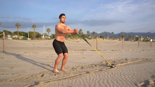 muscular athlete training functional and core exercises performs dragging on the beach with weight a