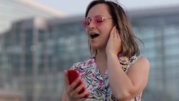 Joyful Woman Tourist in Pink Sunglasses Dancing and Listening To Music in Earphones. Moving in Dance