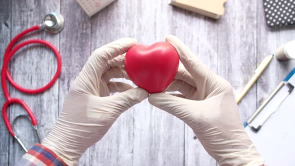 Man Hand in Protective Gloves Holding Red Heart on Blue