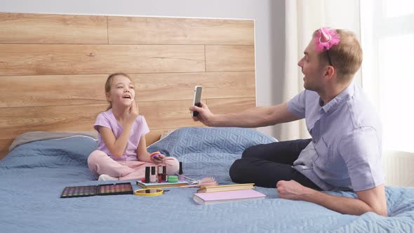 Handsome Young Father Make Video on Smartphone Showing How His Daughter Doing Makeup