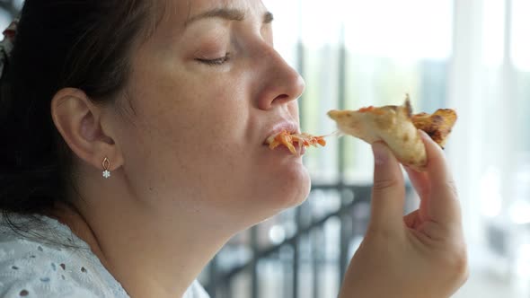 Beautiful Lady in Blue Dress Eating a Slice of Pizza in a Restaurant