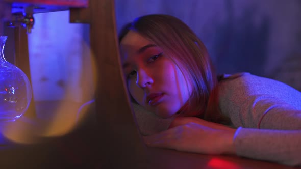 4K Portrait of Loneliness Asian woman sitting in nightclub with illuminated neon night lights