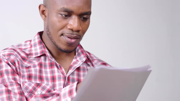 Face close up African man sitting on sofa, holding and checking document