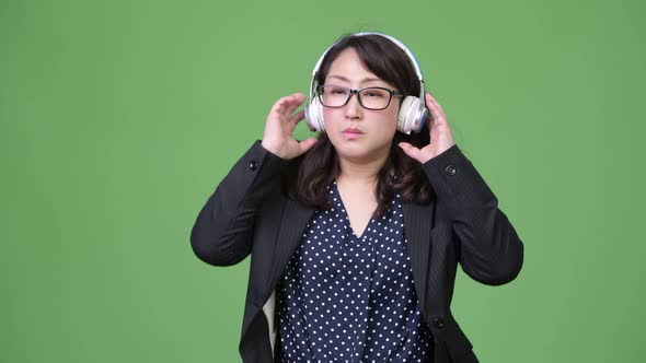 Mature Beautiful Asian Businesswoman Listening To Music