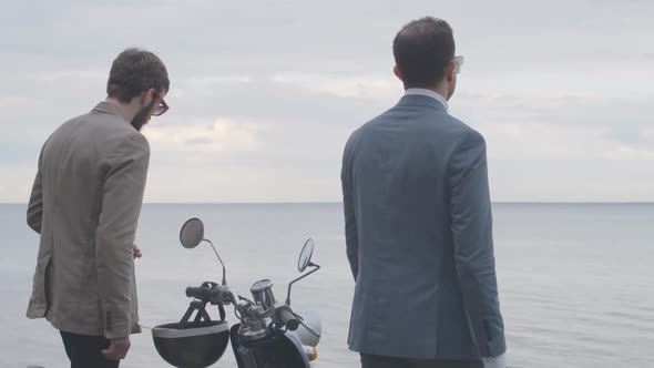 Two Elegant Caucasian Men Walking To River Bank in Slowmo with Scooter Steering Wheel at Front. Back