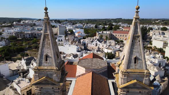 Aerial drone shot fly back between two towers of a cathedral in Alberobello, Italy.