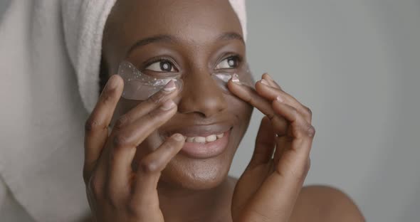 Black Girl with Towel Wrapped on Head Applying Eye Patches