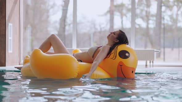 Relax Time in Pool in Thermal Bath Young Woman in Bikini is Lying on Inflatable Cirlce and Floating