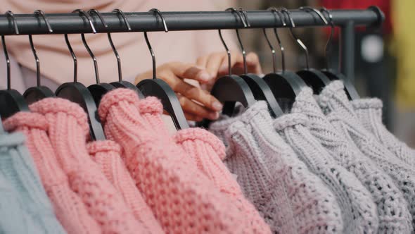 Clothing Store Closeup of Clothes Hanger with Bright Colored Sweaters Female Hands of Unrecognizable