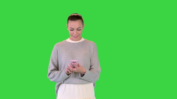 Fashionable Girl Walking and Using Smartphone on a Green Screen Chroma Key
