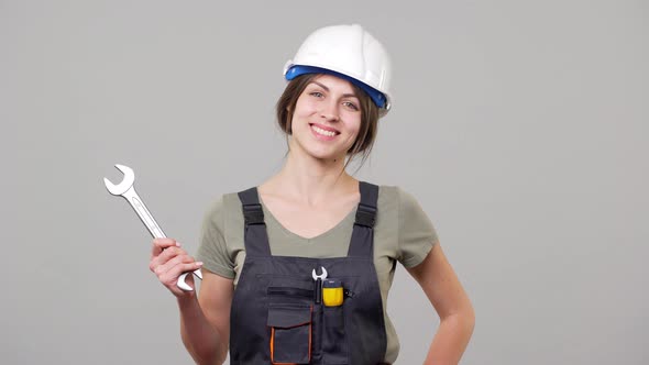 Portrait of Young Woman Engineer or Builder in Helmet and Jumpsuit Working on Factory or