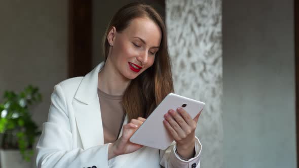 Smiling Woman at Home Sitting on Couch Using Digital Tablet