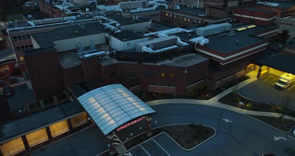 Exterior outside view of hospital emergency room entrance and ambulance parked at night.