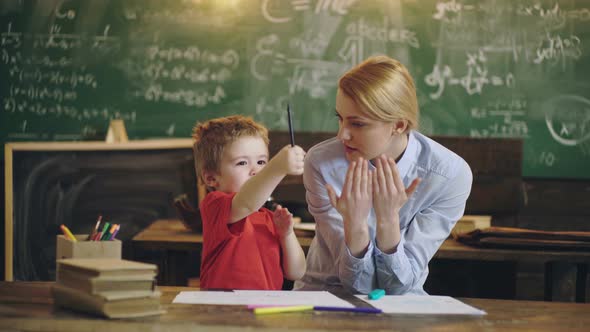 Kid in School. Pretty Teacher Helping Pupil in Classroom at the Elementary School. Schoolboy Boy